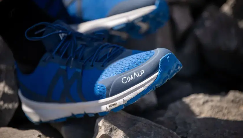 Chaussures de trail bleues CIMALP sur des rochers. Le bon **taille chaussure trail** est essentiel pour l'aventure.