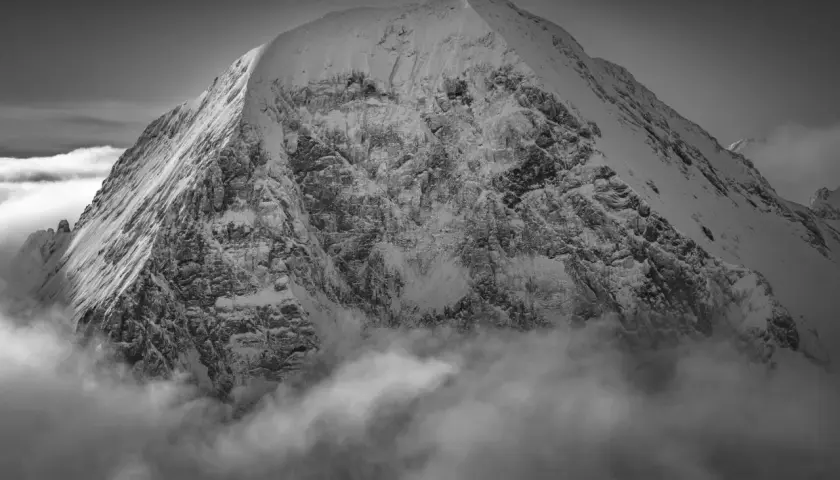 Sommet enneigé émergeant des nuages, une vision spectaculaire capturée par Guido Magnone.