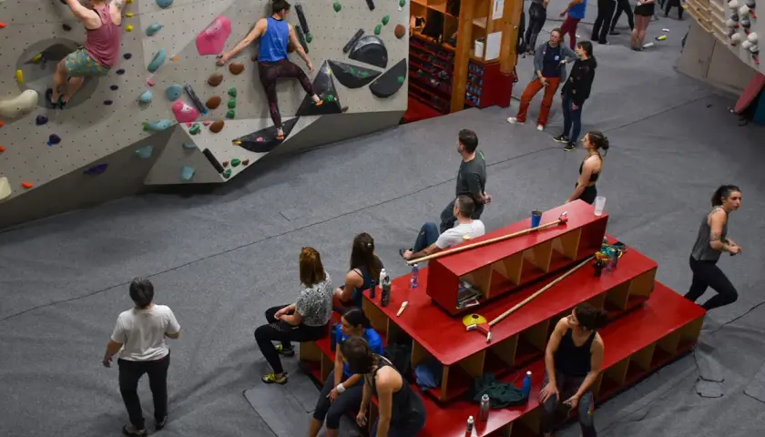Des grimpeurs s'entraînent dans une salle de bloc, atteignant le **hueco zenith** sur des murs colorés.
