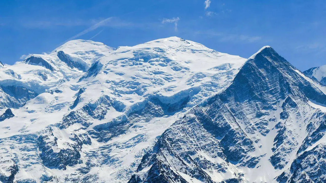 Majestueux Mont Blanc, son versant italien enneigé sous un ciel bleu éclatant. Un paysage alpin à couper le souffle.