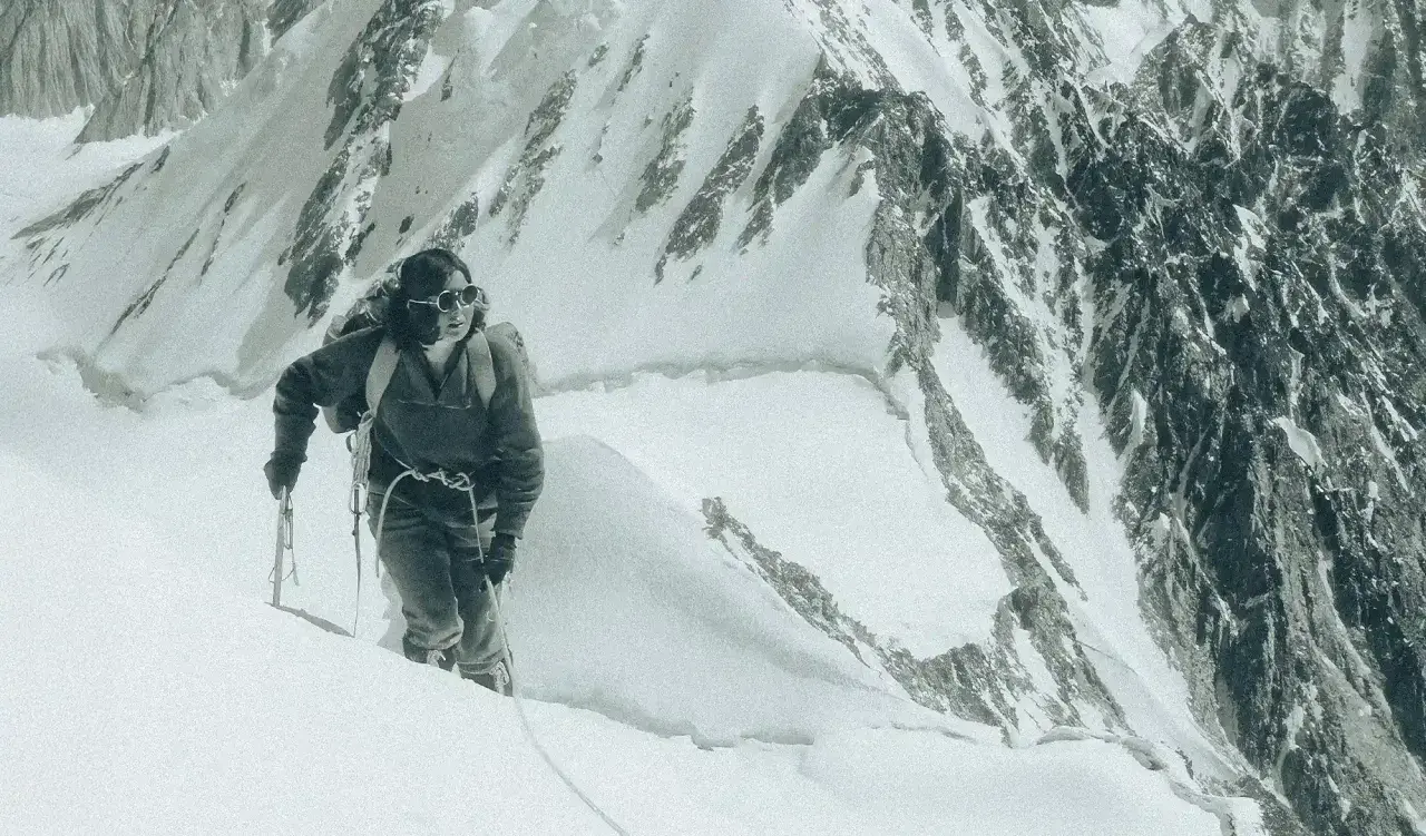 Un alpiniste progresse sur une pente enneigée, crampons aux pieds. Une scène digne d'un podcast alpinisme.
