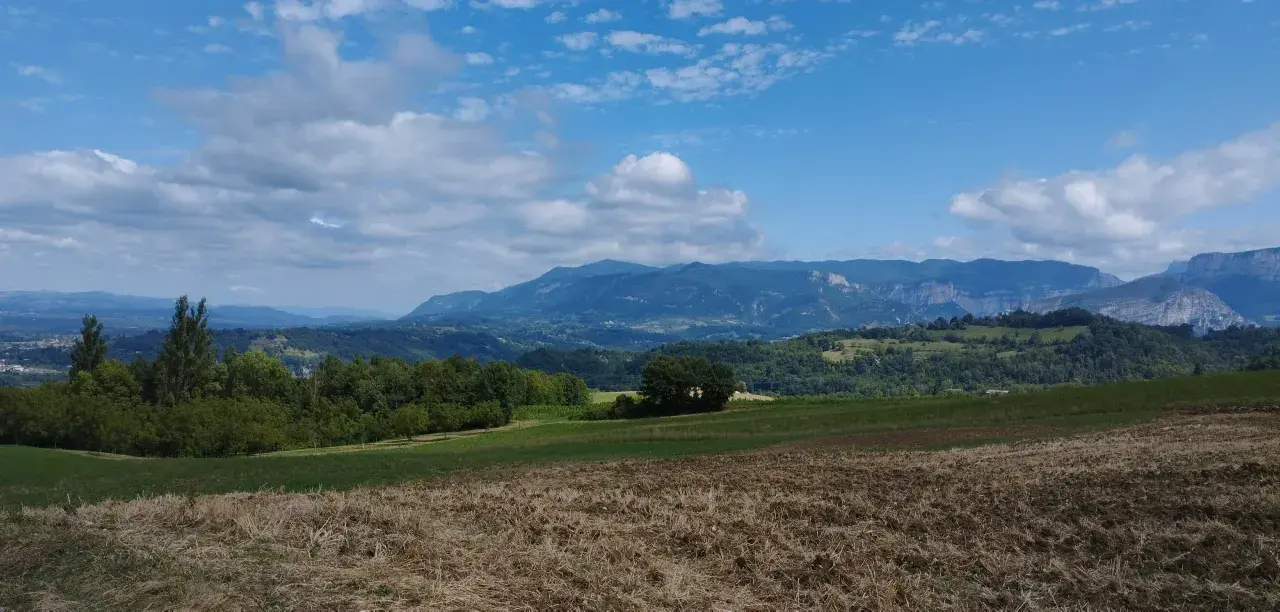 Paysage de montagnes bleues sous un ciel nuageux, parfait pour une randonnée près d'un pont en Royans.