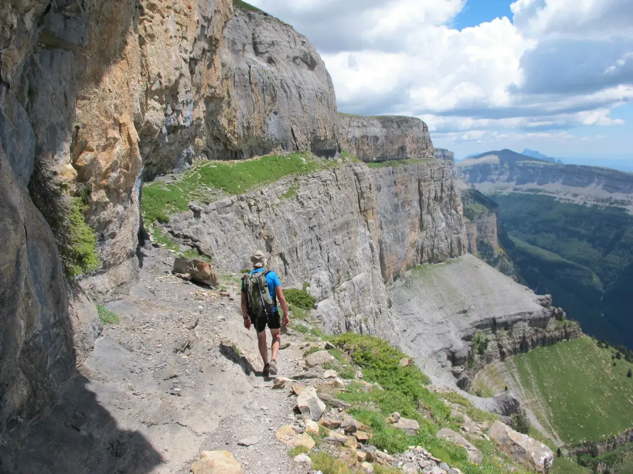 Randonneur sur le sentier escarpé de la Faja de las Flores, dominant un paysage de falaises et de vallées verdoyantes.