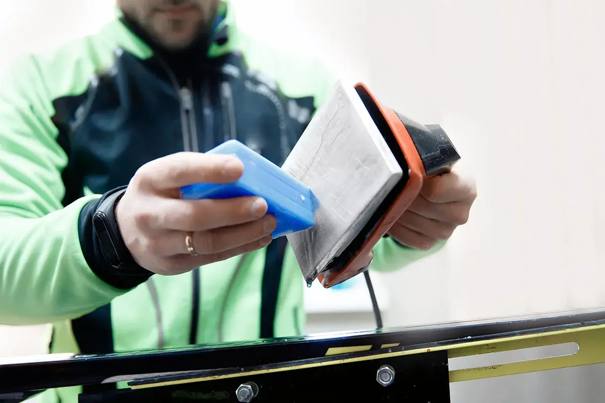 Un skieur prépare ses skis neufs. Il applique de la cire avec un fer chaud, une étape essentielle pour une glisse optimale.