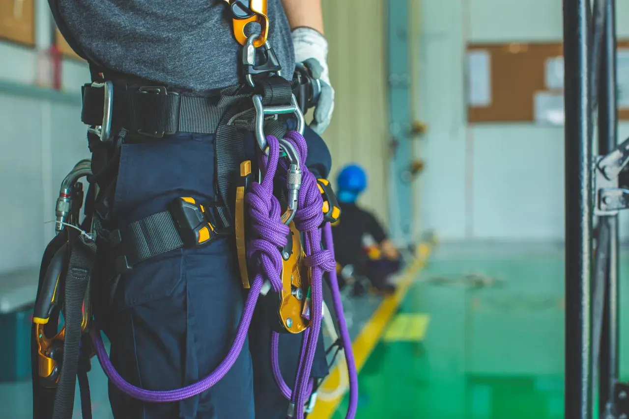 Un travailleur porte un harnais de sécurité avec une cordelette violette. Il est prêt pour une intervention en hauteur.
