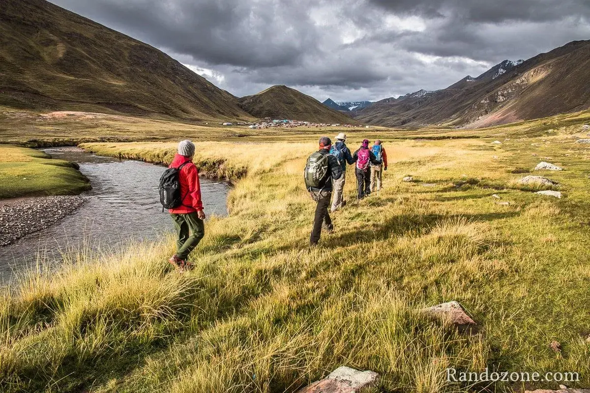 Un groupe de randonneurs s'engage dans un trek de 5 jours en France, traversant une vallée verdoyante avec une rivière sinueuse.