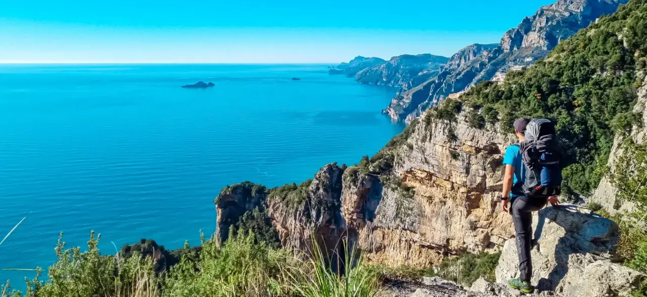Randonnée sur la côte amalfitaine. Un randonneur admire la vue spectaculaire sur la mer bleue et les falaises escarpées.