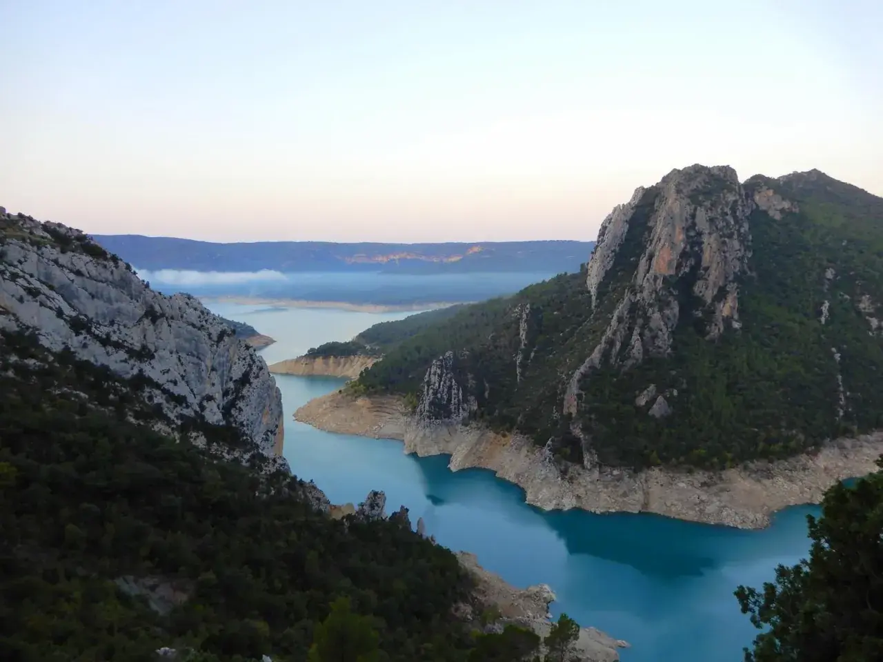 Vue spectaculaire des **pasarelas de Montfalcó** serpentant entre des falaises rocheuses et un lac aux eaux turquoise.