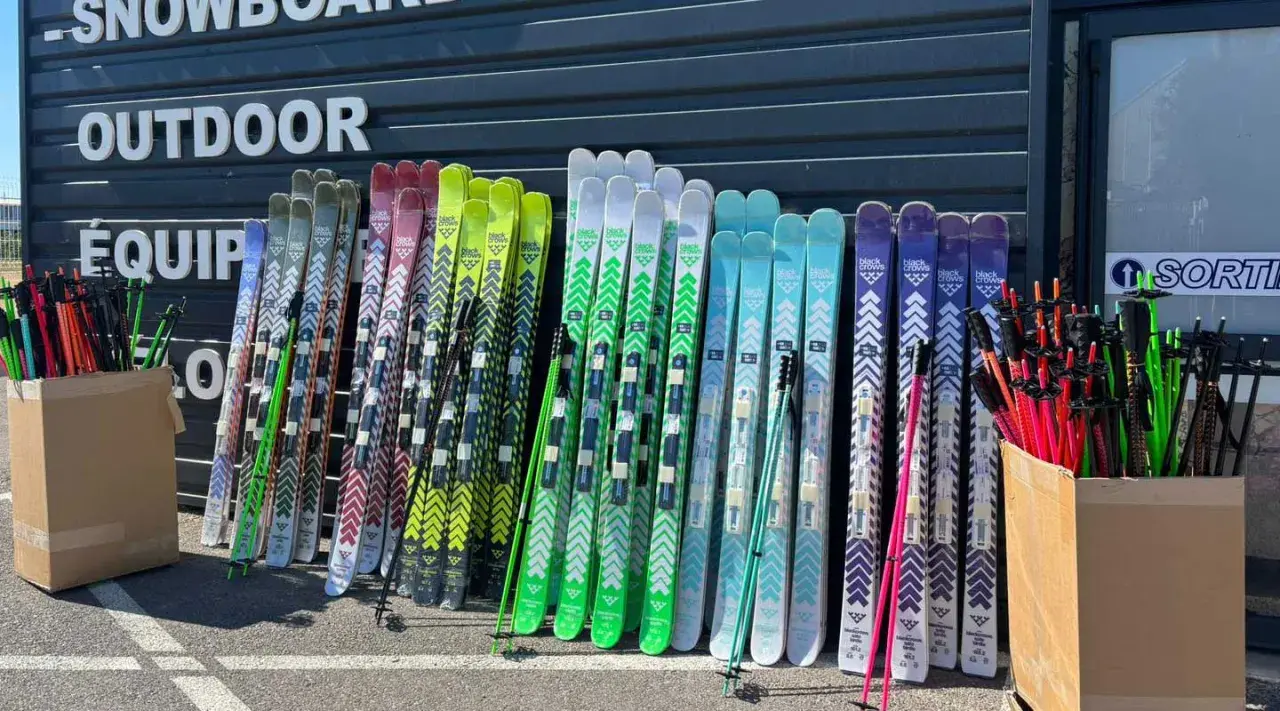 Une rangée de skis de différentes couleurs, certains avec des motifs chevron, prêts pour le freeride. La **taille ski freeride** varie pour s'adapter à tous les riders.