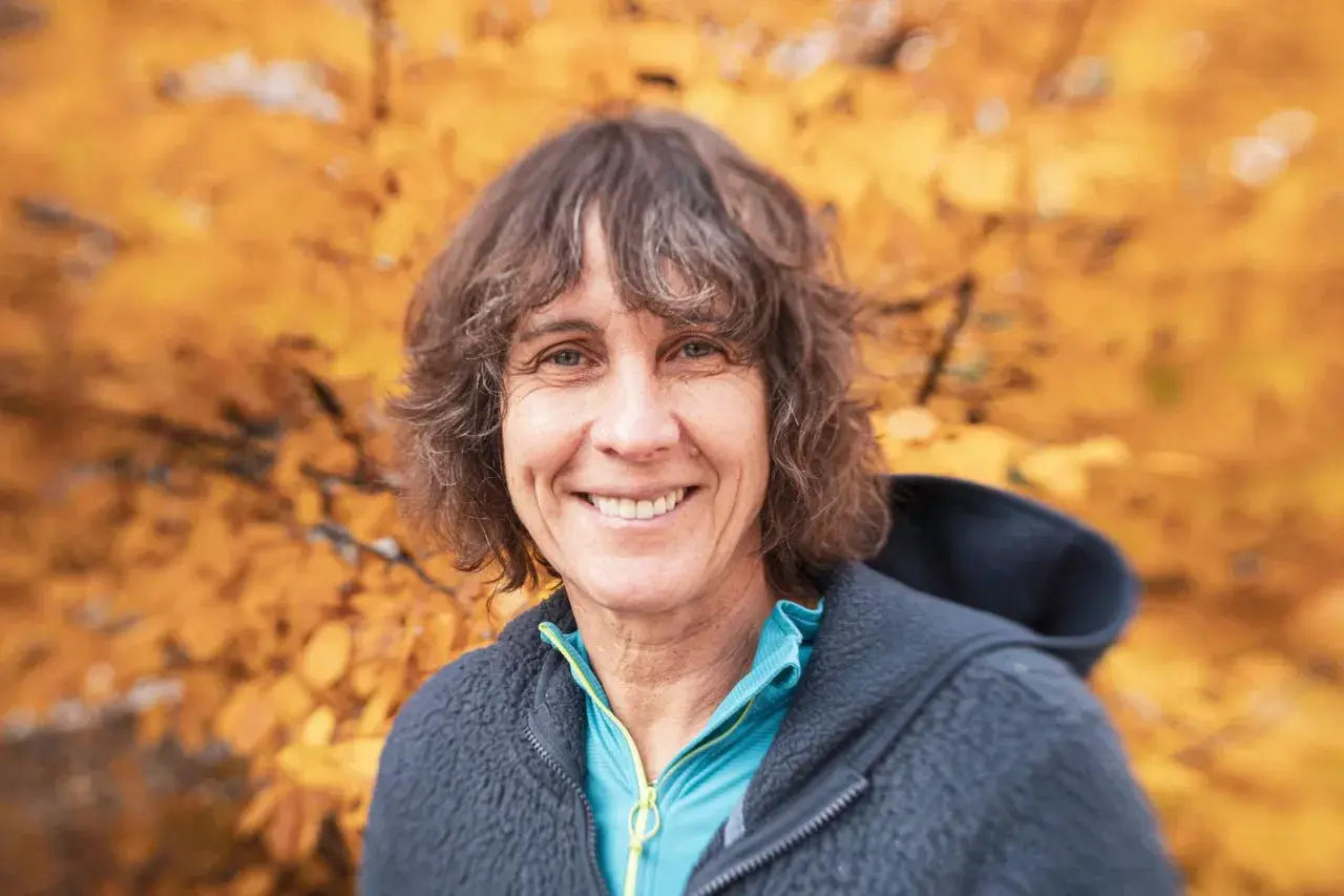 Catherine Destivelle, souriante, en tenue de sport, avec un fond d'automne. Elle est une alpiniste reconnue, un vrai compagnon de la nature.