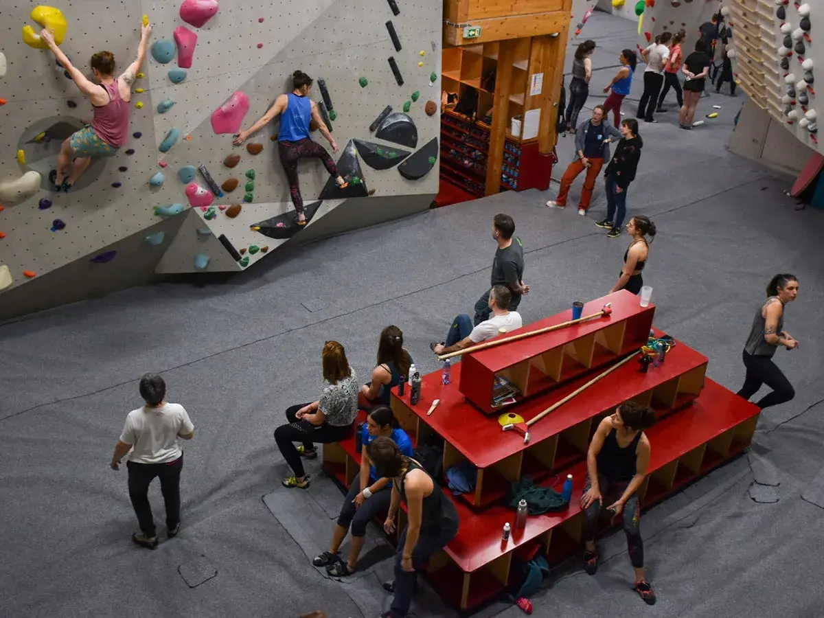 Des grimpeurs s'entraînent dans une salle de bloc, atteignant le **hueco zenith** sur des murs colorés.