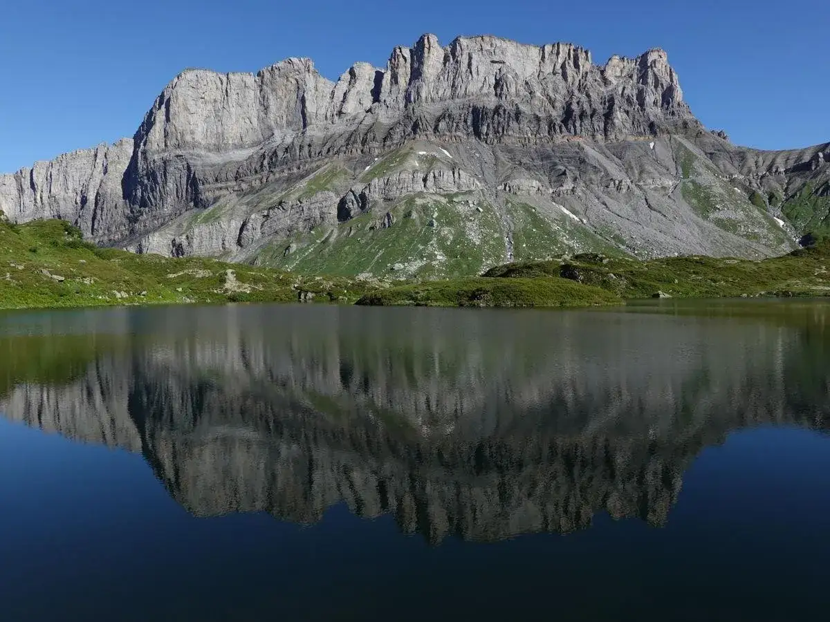 Reflet d'une montagne rocheuse dans un lac alpin paisible. Les f&icirc;z de la roche se dressent fi&egrave;rement, refl&eacute;tant leur majest&eacute; dans l'eau calme.