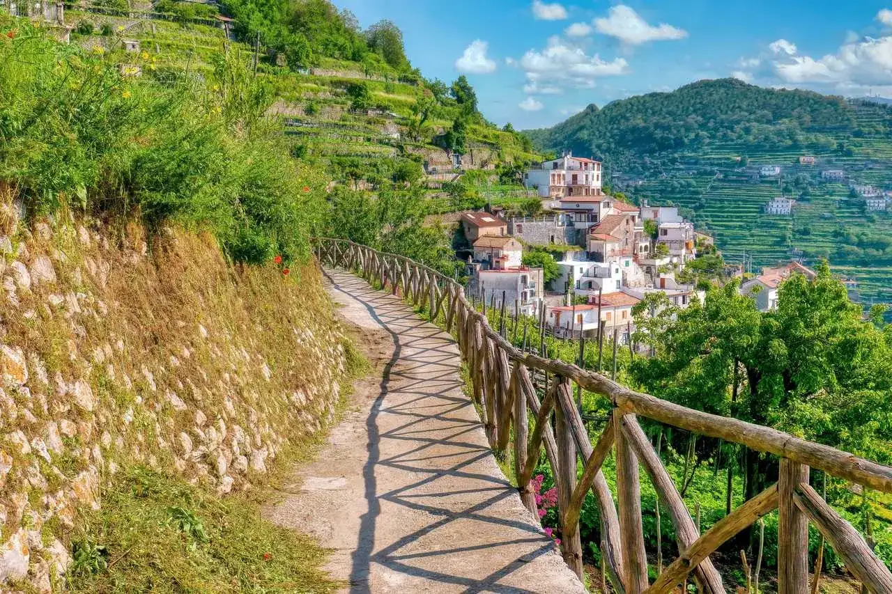 Sentier ensoleill&eacute; sur la c&ocirc;te Amalfitaine, menant &agrave; un village pittoresque nich&eacute; sur les pentes verdoyantes. Parfait pour une randonn&eacute;e m&eacute;morable.