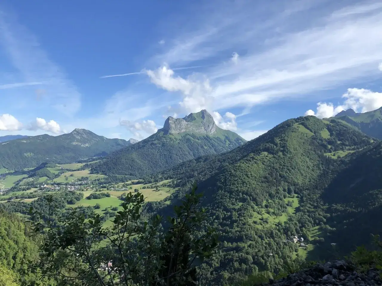 Vue panoramique des montagnes verdoyantes des Bauges sous un ciel bleu parsemé de nuages. Idéal pour une randonnée.