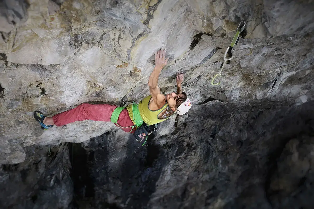Angela Eiter, escaladeuse, s'accroche à la paroi rocheuse, concentrée sur sa prochaine prise.