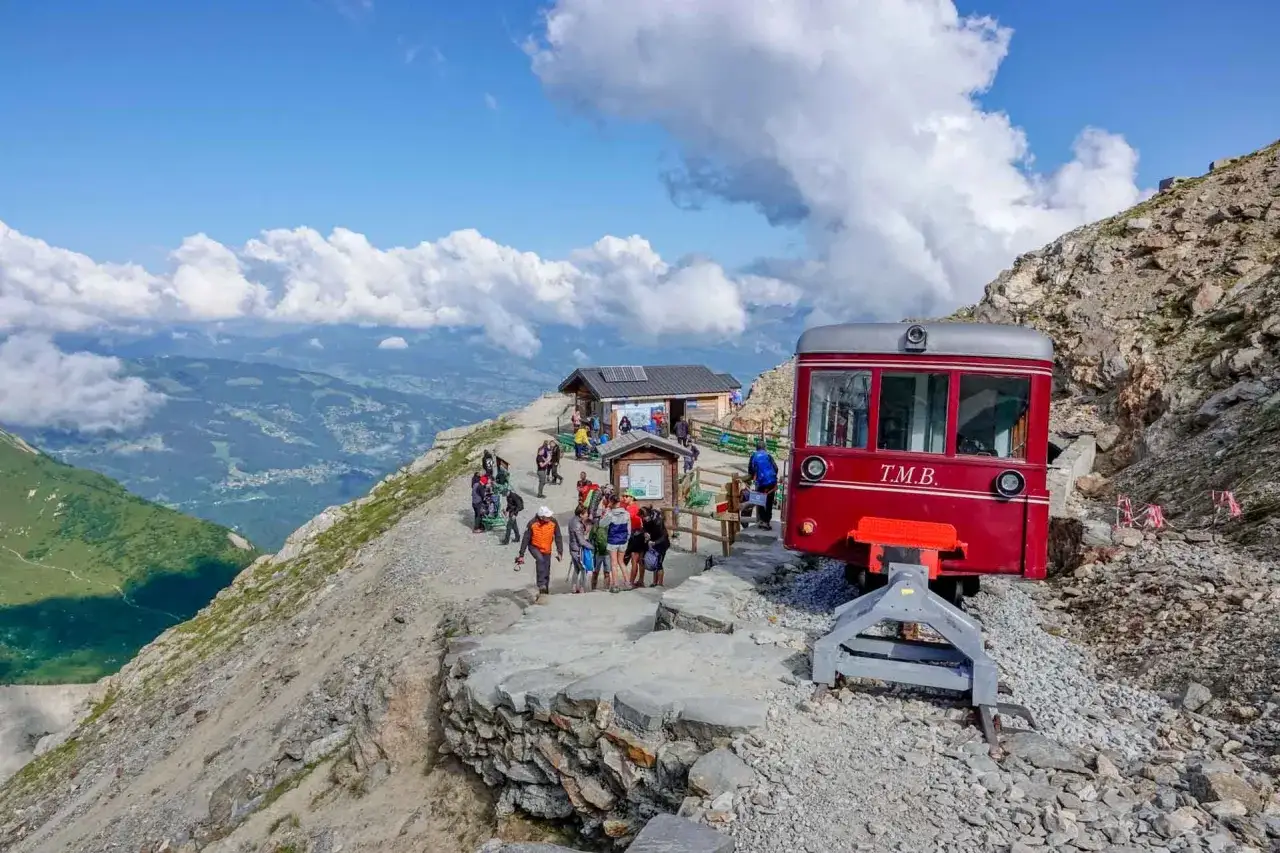 Un train rouge attend les visiteurs pour leur montrer comment se rendre au nid d'aigle. La gare de montagne offre une vue spectaculaire sur la vallée.