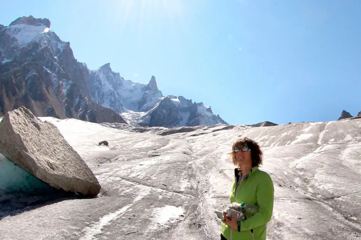 Catherine Destivelle, en compagnie d'un compagnon imaginaire, sourit face &agrave; un paysage de haute montagne enneig&eacute;e.