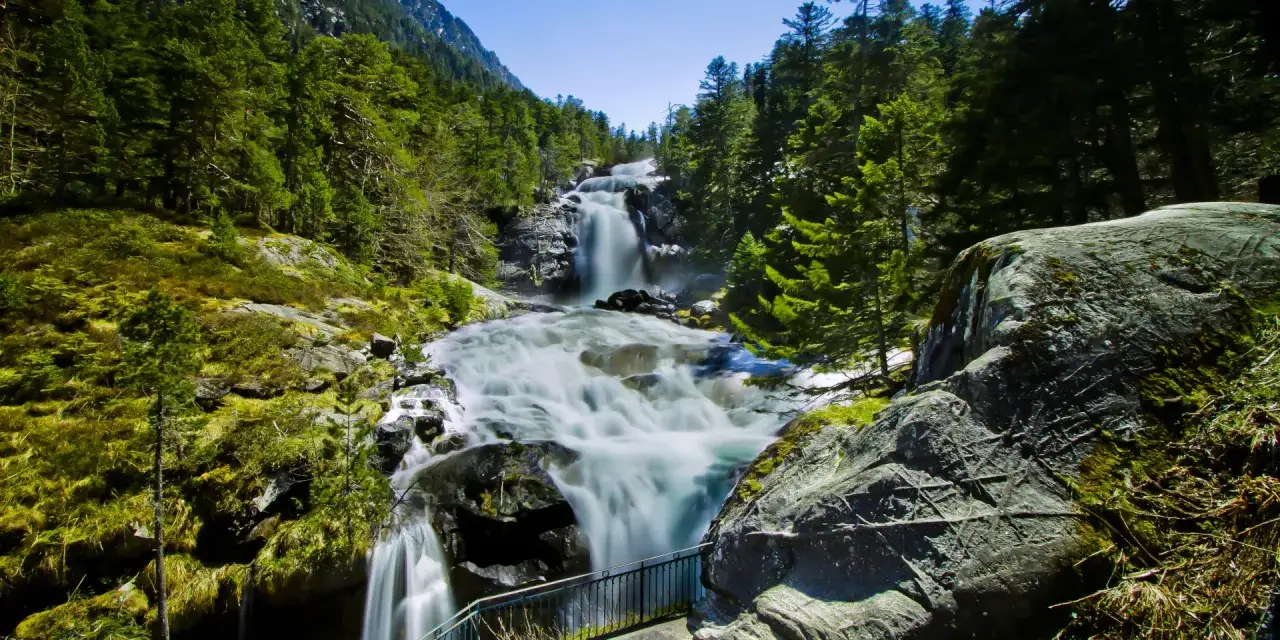 Le chemin des cascades à Cauterets offre une vue spectaculaire sur une chute d'eau puissante, entourée de verdure luxuriante et de rochers moussus.
