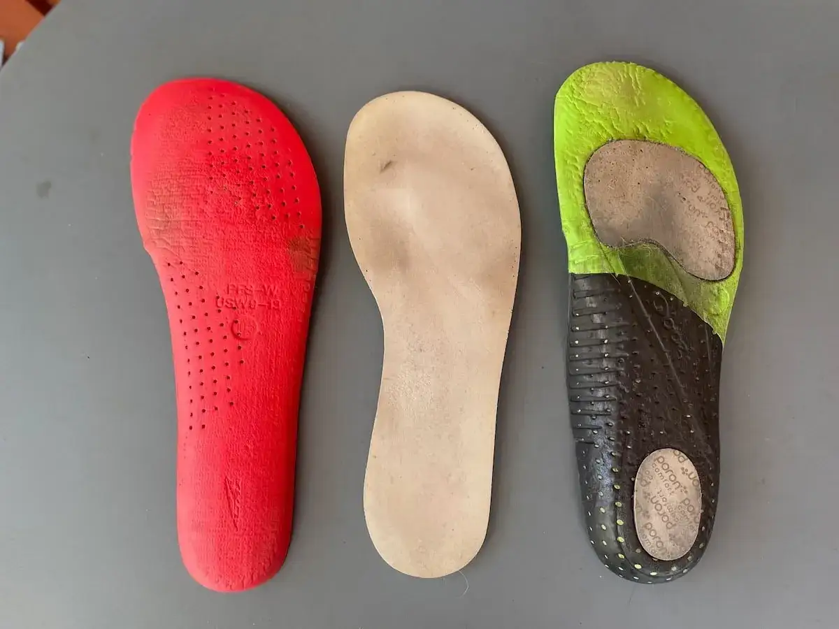 Trois semelles de propreté : une rouge perforée, une beige simple, et une verte/noire usée. Elles montrent ce qu'est une semelle de propreté.