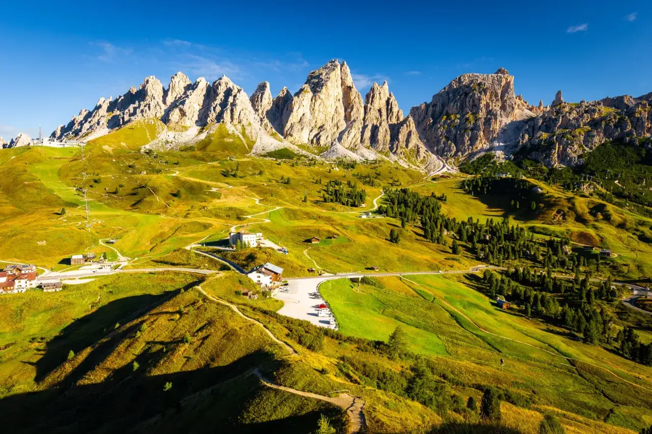 Paysage de montagne spectaculaire, avec des pics rocheux imposants et des pentes verdoyantes travers&eacute;es par des sentiers. L'Alta Via 2 des Dolomites offre une vue imprenable.