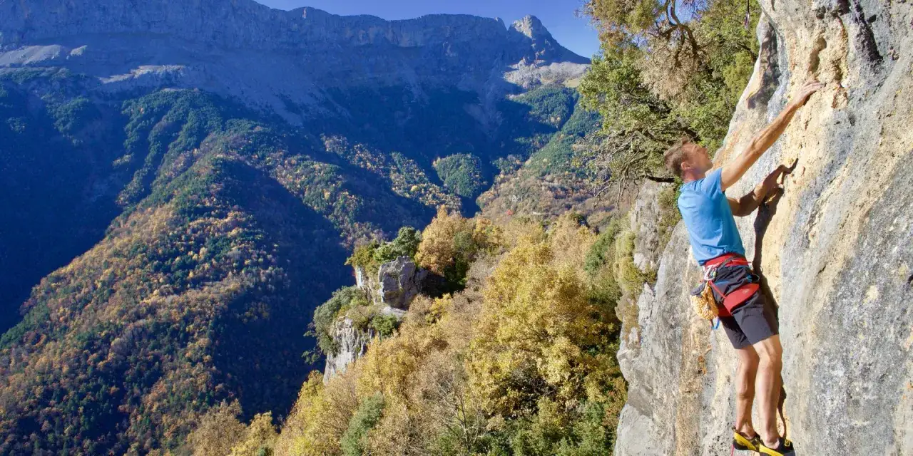 Un grimpeur défie la roche dans un paysage spectaculaire des Pyrénées en automne. L'escalade pyrénéenne offre des vues à couper le souffle.