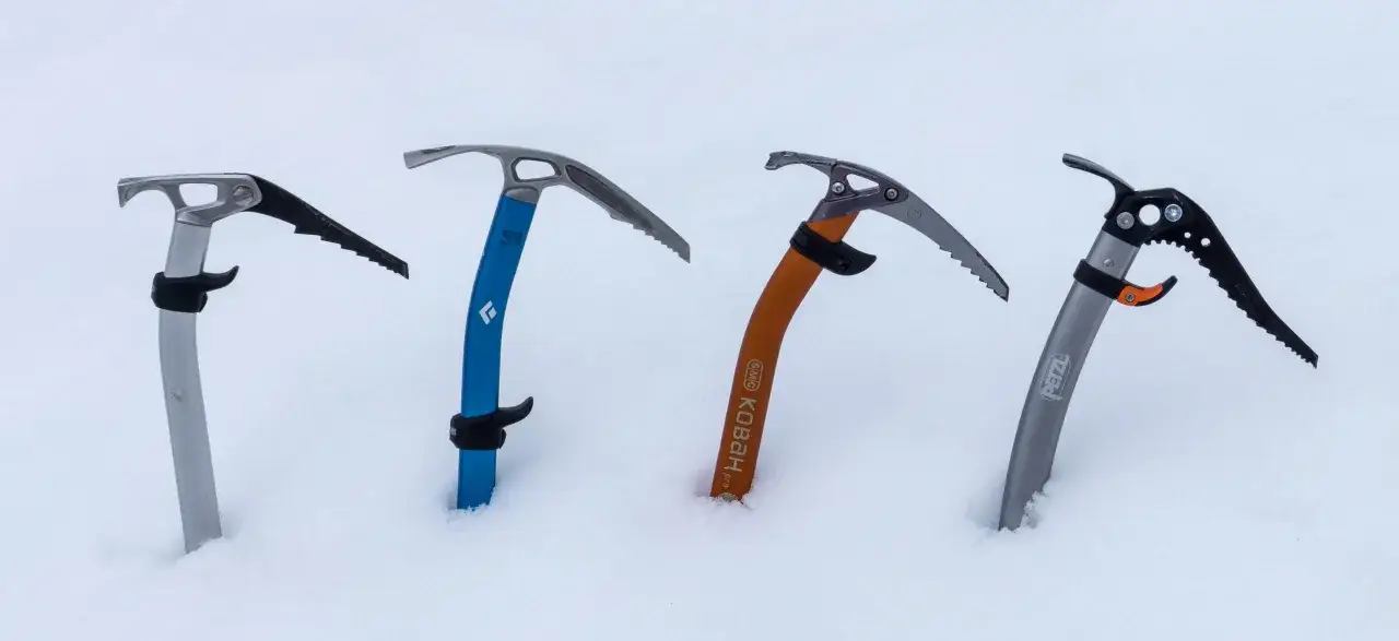 Quatre piolets de montagne, pr&ecirc;ts pour l'aventure, plant&eacute;s dans la neige.