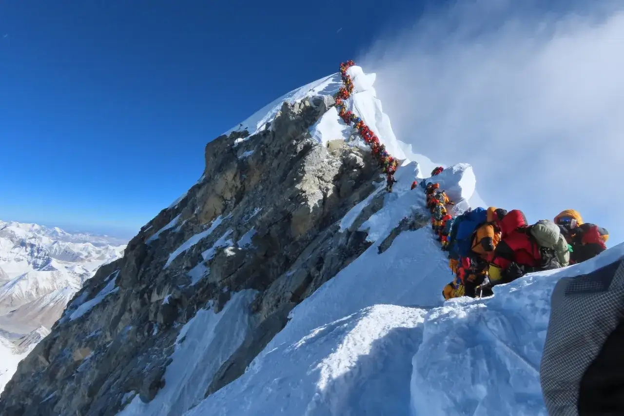 Une longue file de grimpeurs colorés sur l'arête enneigée de l'Everest, un exploit rendu possible par des pionniers comme Nirmal Purja.