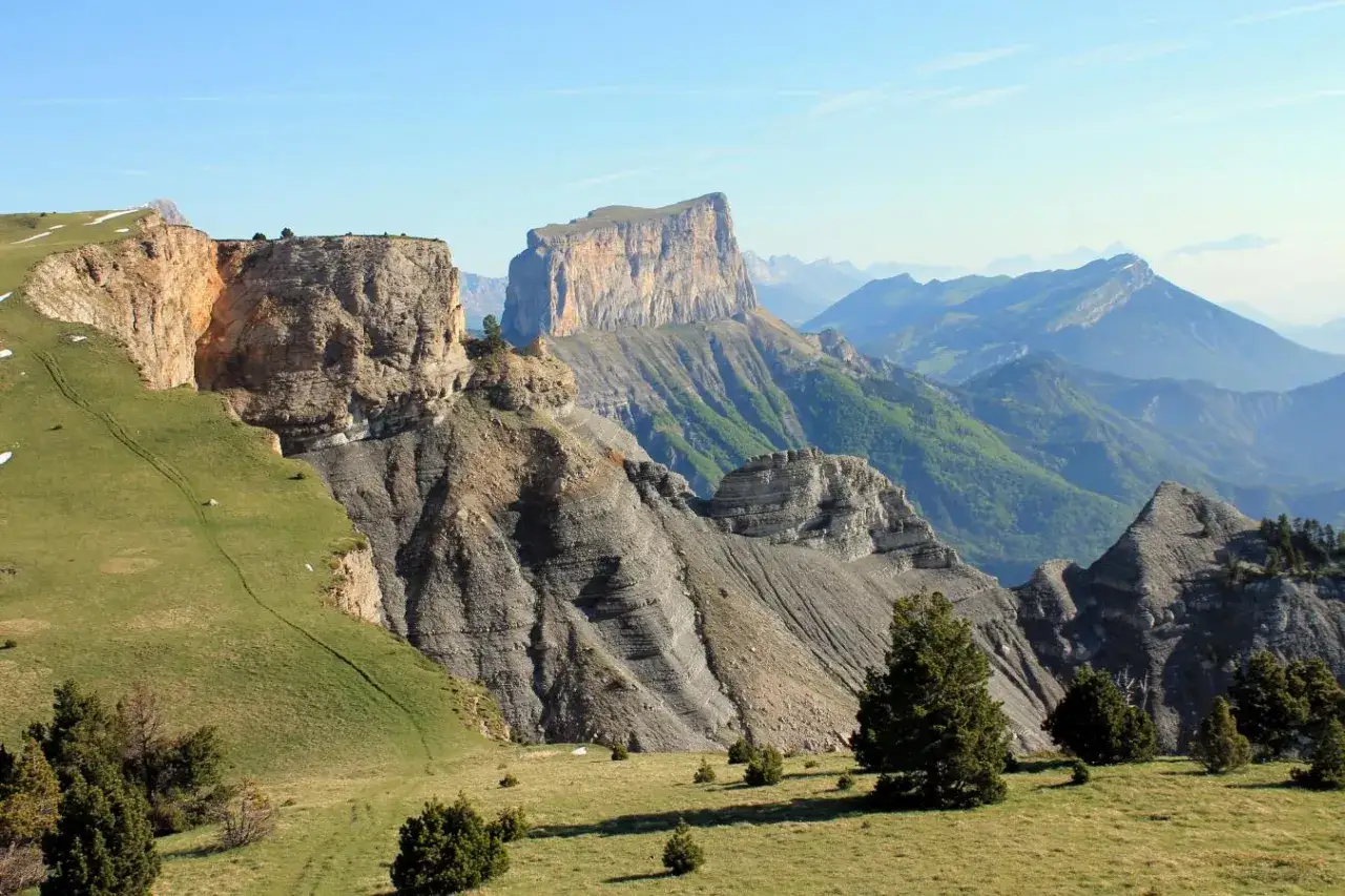 Paysage spectaculaire du Vercors en &eacute;t&eacute;, avec ses falaises calcaires imposantes, ses pentes verdoyantes et ses montagnes bleut&eacute;es &agrave; l'horizon. Id&eacute;al pour savoir o&ugrave; aller dans le Vercors en &eacute;t&eacute;.