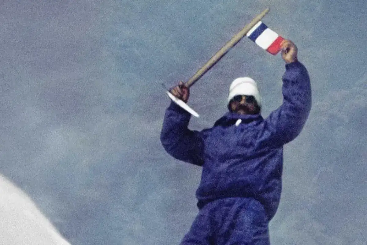 Les mains de Maurice Herzog brandissent un drapeau fran&ccedil;ais au sommet.
