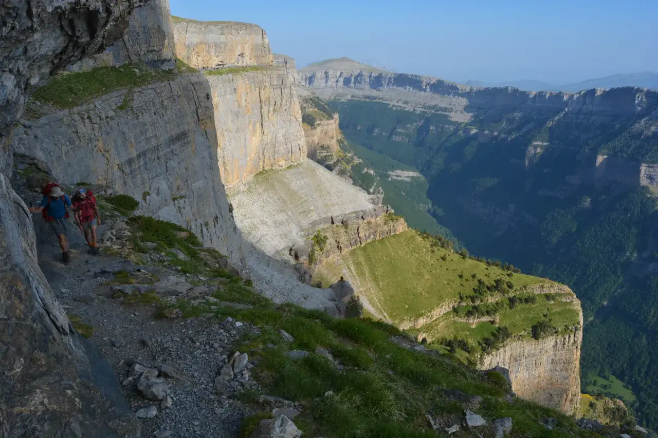 Deux randonneurs sur le sentier escarpé de la Faja de las Flores, dominant un canyon verdoyant.