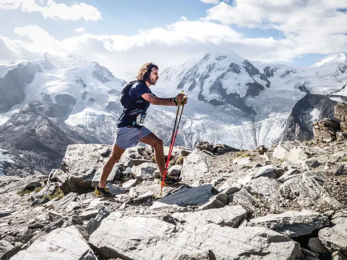 Victor Decamp Destivelle, athl&egrave;te en trail, progresse sur un sentier rocheux face &agrave; des montagnes enneig&eacute;es majestueuses.