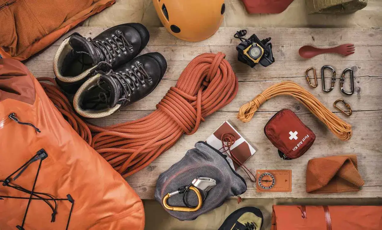 Vue a&eacute;rienne d'une liste de mat&eacute;riel d'escalade : chaussures, cordes, casque, mousquetons, trousse de premiers secours, boussole et sac &eacute;tanche.