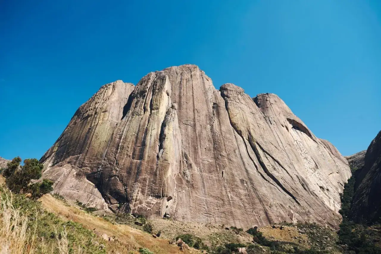 Immense paroi rocheux sous un ciel bleu intense, parfait pour l'escalade à Madagascar. La roche striée par le temps invite à l'aventure.