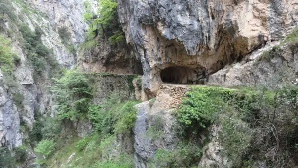 Sentier creusé dans la roche, le long de la ruta del Cares dans les Picos de Europa. Un tunnel naturel s'ouvre sur le chemin.